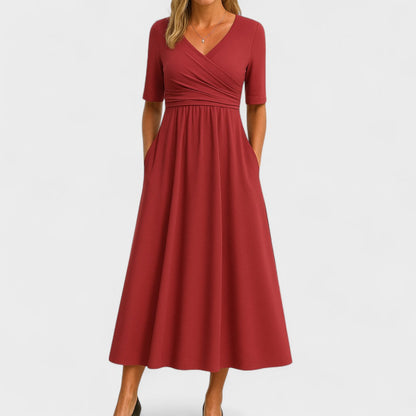 Red - A woman wearing a heather gray jersey knit midi dress featuring a surplice V-neckline, ruched wrap bodice, short sleeves, and a flowy A-line skirt with side pockets.
