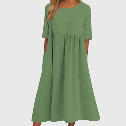Green - A woman wearing a solid white linen-blend midi dress with a scoop neckline, elbow-length half sleeves, a gathered empire waist, and a flowy skirt with side pockets.