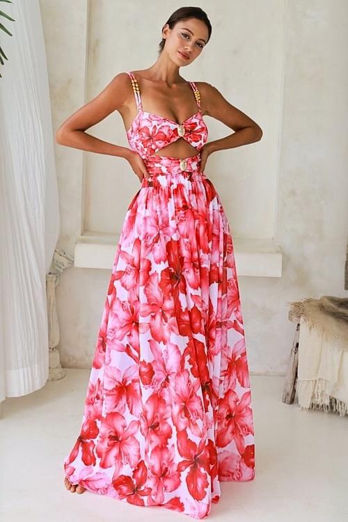 Woman in pink and red floral chiffon maxi dress with cutout waist.