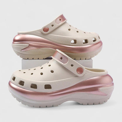 Black - Molded foam slip-on platform clogs featuring ventilation ports across the upper, a pivoting heel strap, and a distinct metallic trim along the thick midsole