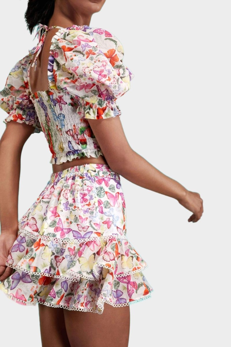Woman wearing butterfly print crop top and ruffle skirt set