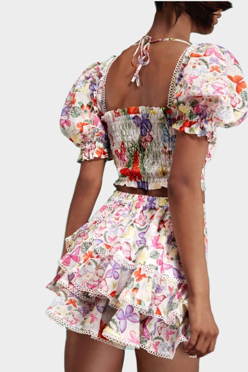 Woman wearing butterfly print crop top and ruffle skirt set