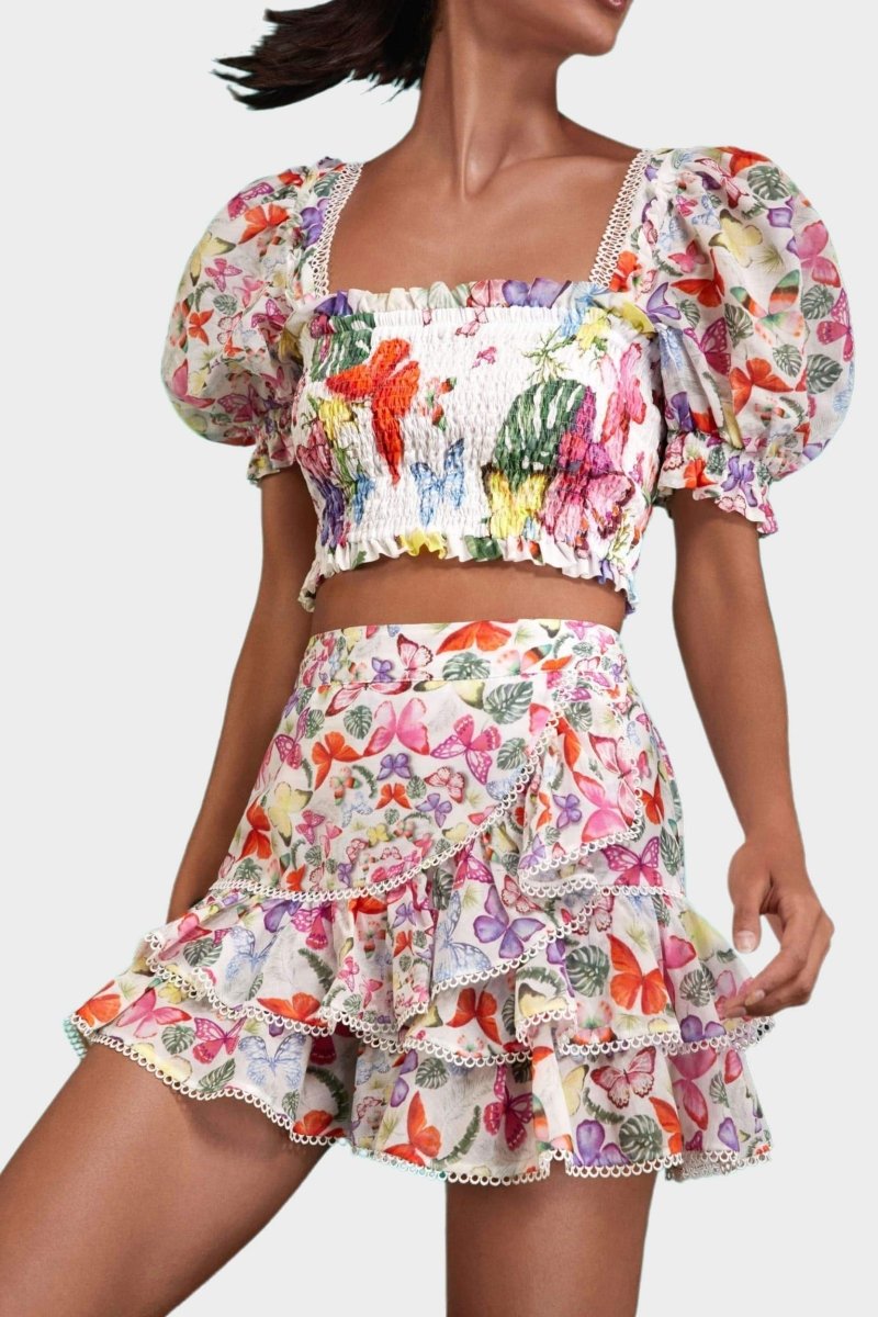Woman wearing butterfly print crop top and ruffle skirt set