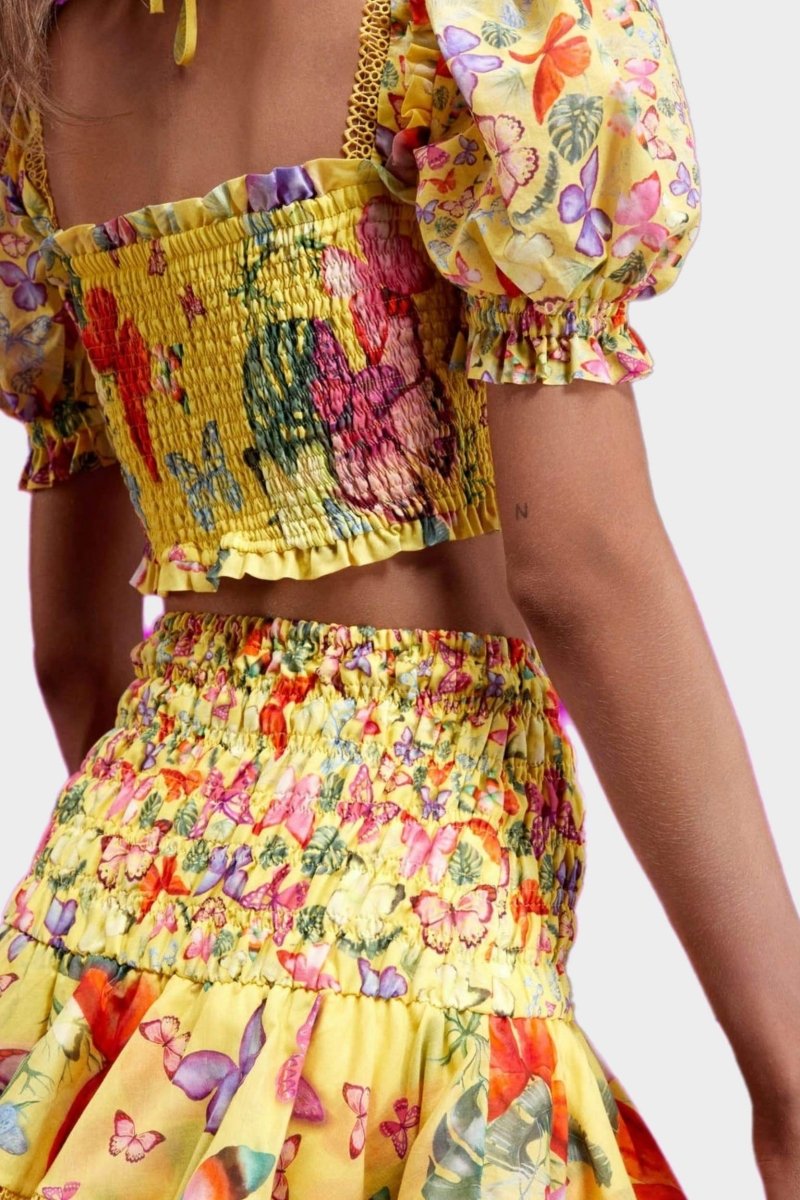 Woman wearing butterfly print crop top and ruffle skirt set