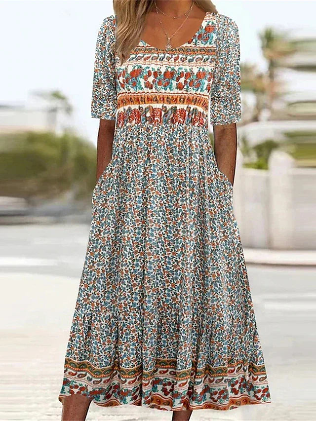 Multicolor - A woman wearing a bohemian-style maxi sundress featuring a multi-colored paisley and ditsy floral print, scoop neckline, half sleeves, and functional side pockets.