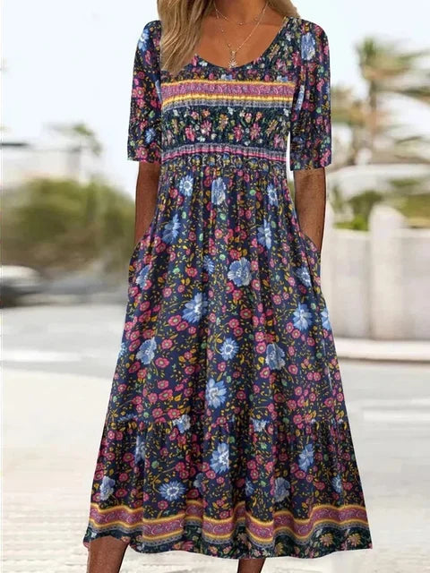 Multicolor4 - A woman wearing a bohemian-style maxi sundress featuring a multi-colored paisley and ditsy floral print, scoop neckline, half sleeves, and functional side pockets.