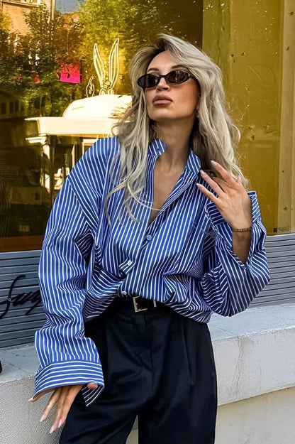 Woman wearing oversized blue and white striped shirt with black pants and sunglasses