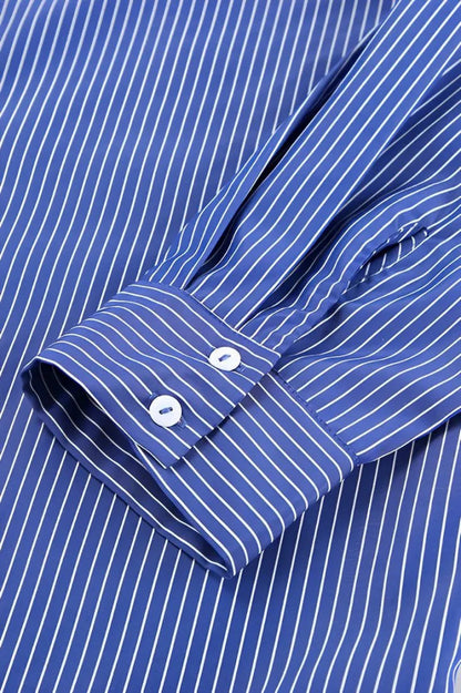 Woman wearing oversized blue and white striped shirt with black pants and sunglasses
