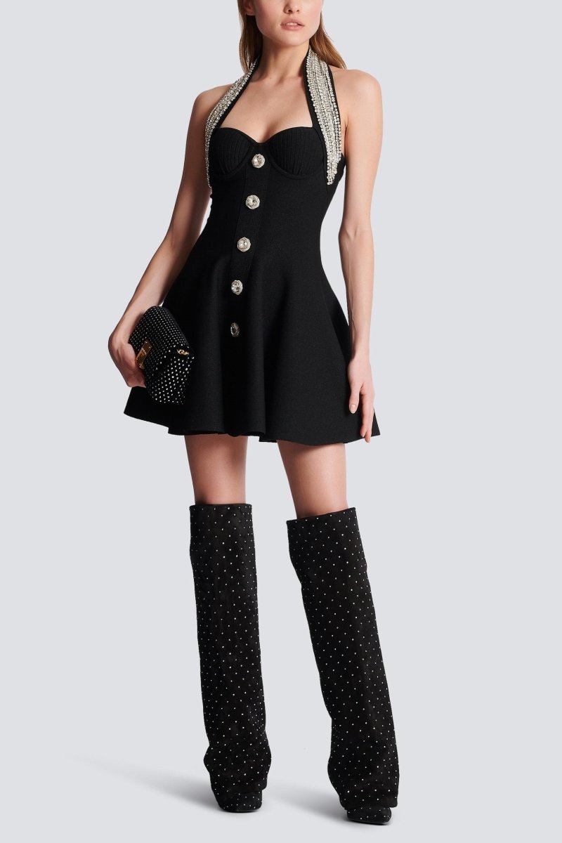 Woman wearing black mini dress with crystal halter neck and decorative buttons