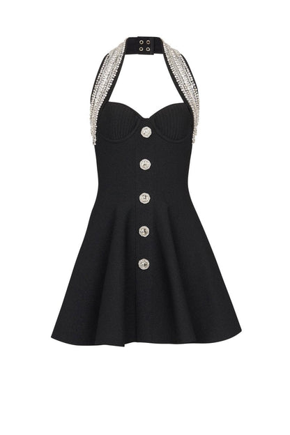 Woman wearing black mini dress with crystal halter neck and decorative buttons