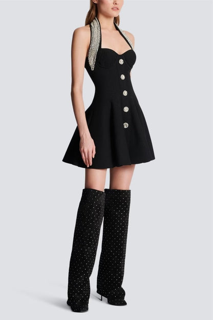Woman wearing black mini dress with crystal halter neck and decorative buttons