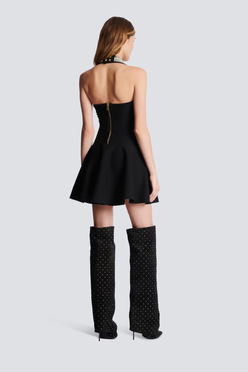 Woman wearing black mini dress with crystal halter neck and decorative buttons