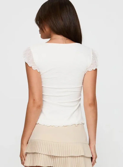 Woman wearing white textured cotton top with ruffle sleeves and tie front