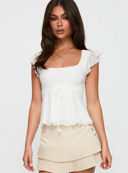 Woman wearing white textured cotton top with ruffle sleeves and tie front