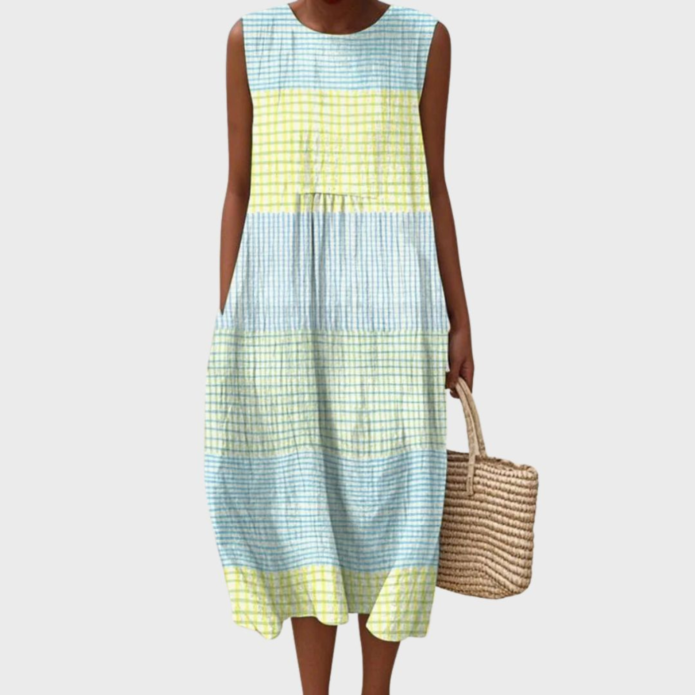 Light Blue - Woman wearing a sleeveless, plaid midi sundress with a pleated waist and side pockets, holding a woven straw bag.
