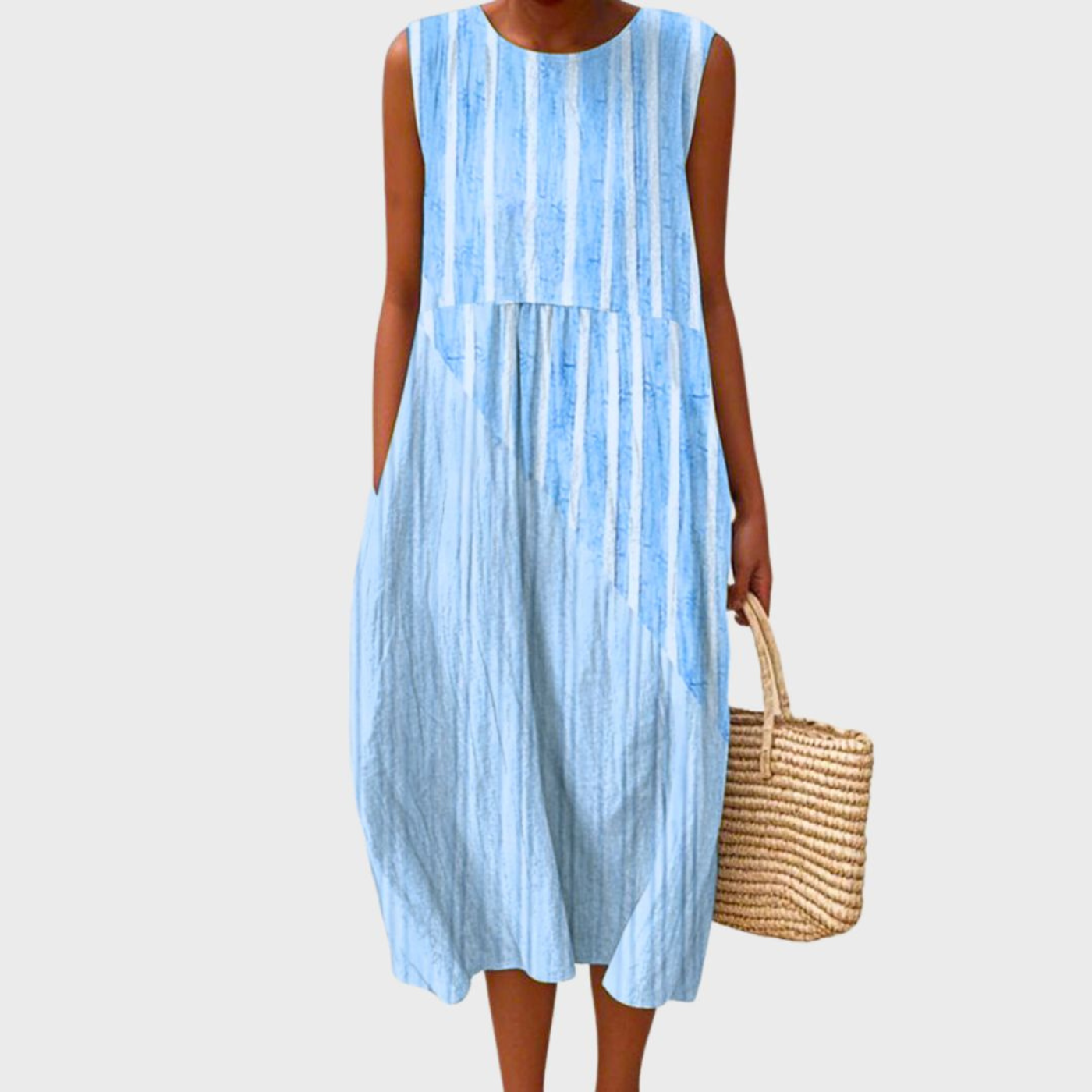 Light Blue 2 - Woman wearing a sleeveless, plaid midi sundress with a pleated waist and side pockets, holding a woven straw bag.
