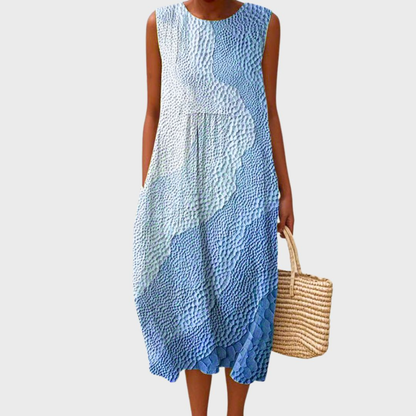 Steel Blue - Woman wearing a sleeveless, plaid midi sundress with a pleated waist and side pockets, holding a woven straw bag.