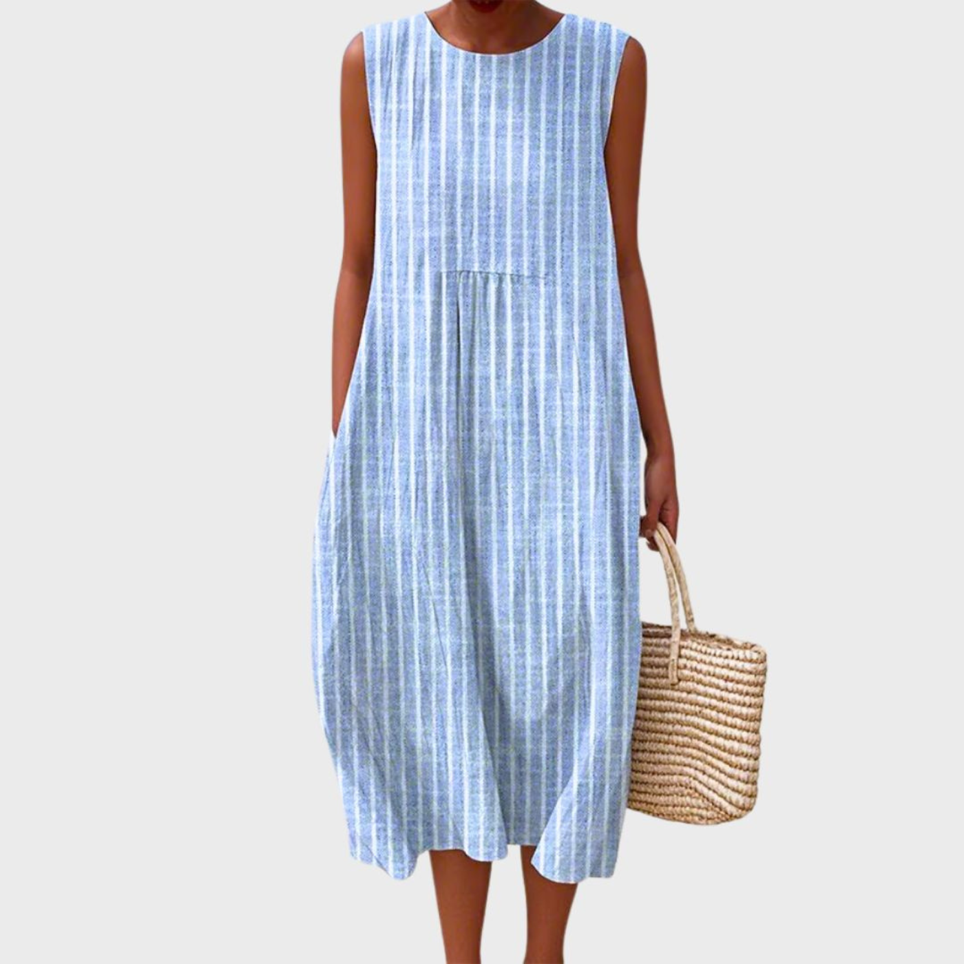 Blue - Woman wearing a sleeveless, plaid midi sundress with a pleated waist and side pockets, holding a woven straw bag.