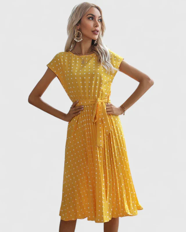 Yellow - A woman wearing a dusty pink midi dress with white polka dots, featuring cap sleeves, a belted waist, and a pleated skirt.