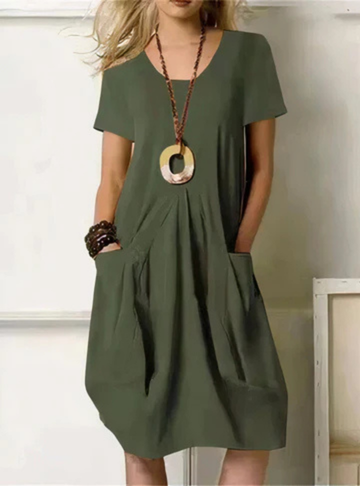 Army Green - Woman wearing a solid color short sleeve knee-length shift dress featuring front pleats and two large patch pockets