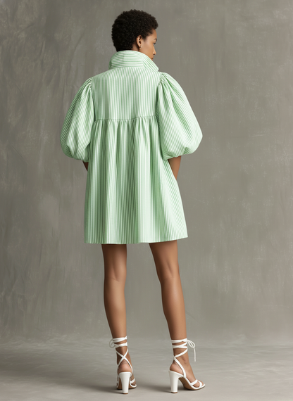Light Green - Model wearing a striped poplin mini dress featuring voluminous puff sleeves, a high stand collar, front half-zip closure, and side pockets, styled with a chunky chain necklace and strappy heels.
