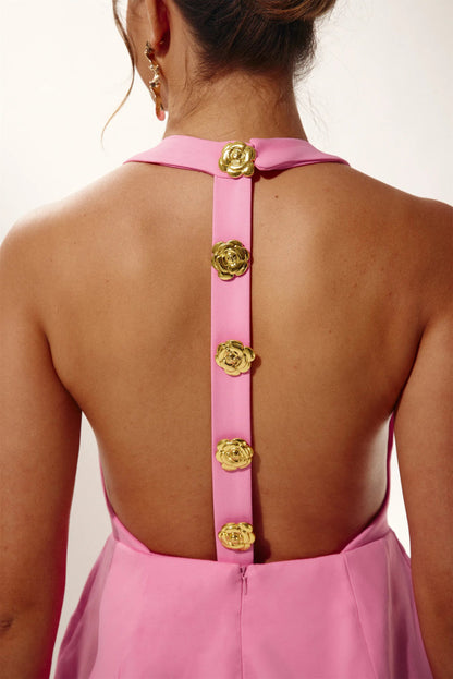 Woman in pink crepe mini dress with gold rose buttons