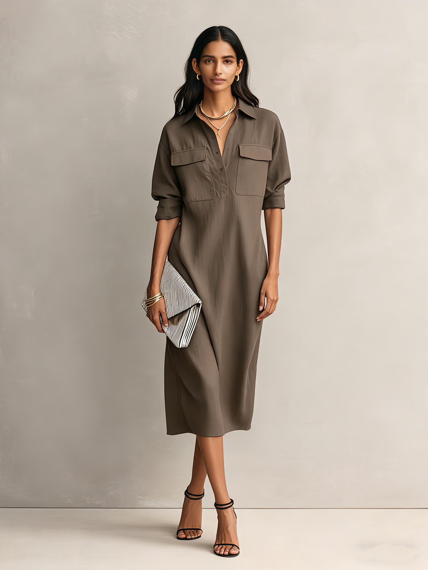 Cool Brown - Model wearing a relaxed fit collared midi shirtdress with chest pockets and rolled sleeves, styled with gold jewelry and strappy heels