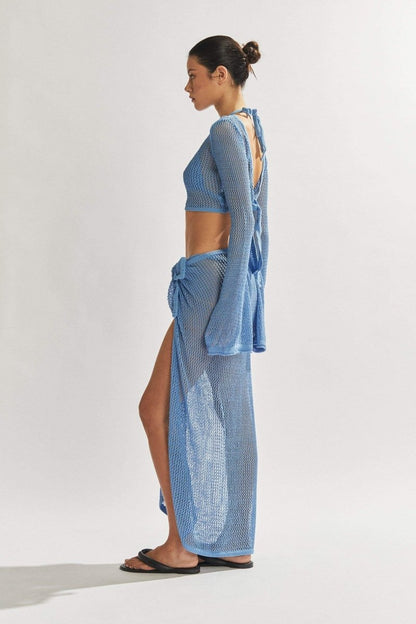 Woman in light blue crochet knit crop top and maxi skirt.
