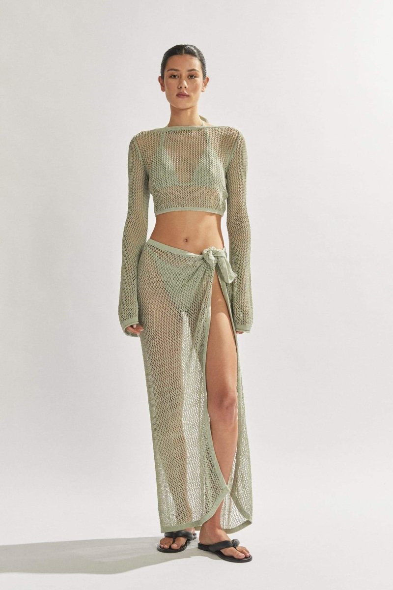 Woman in light blue crochet knit crop top and maxi skirt.