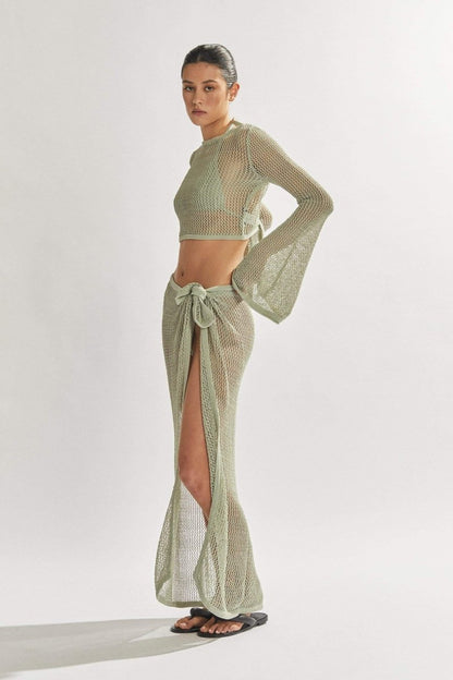 Woman in light blue crochet knit crop top and maxi skirt.