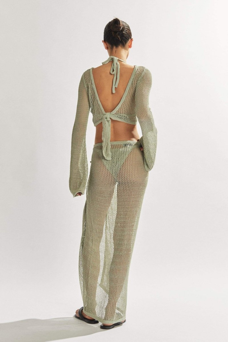 Woman in light blue crochet knit crop top and maxi skirt.