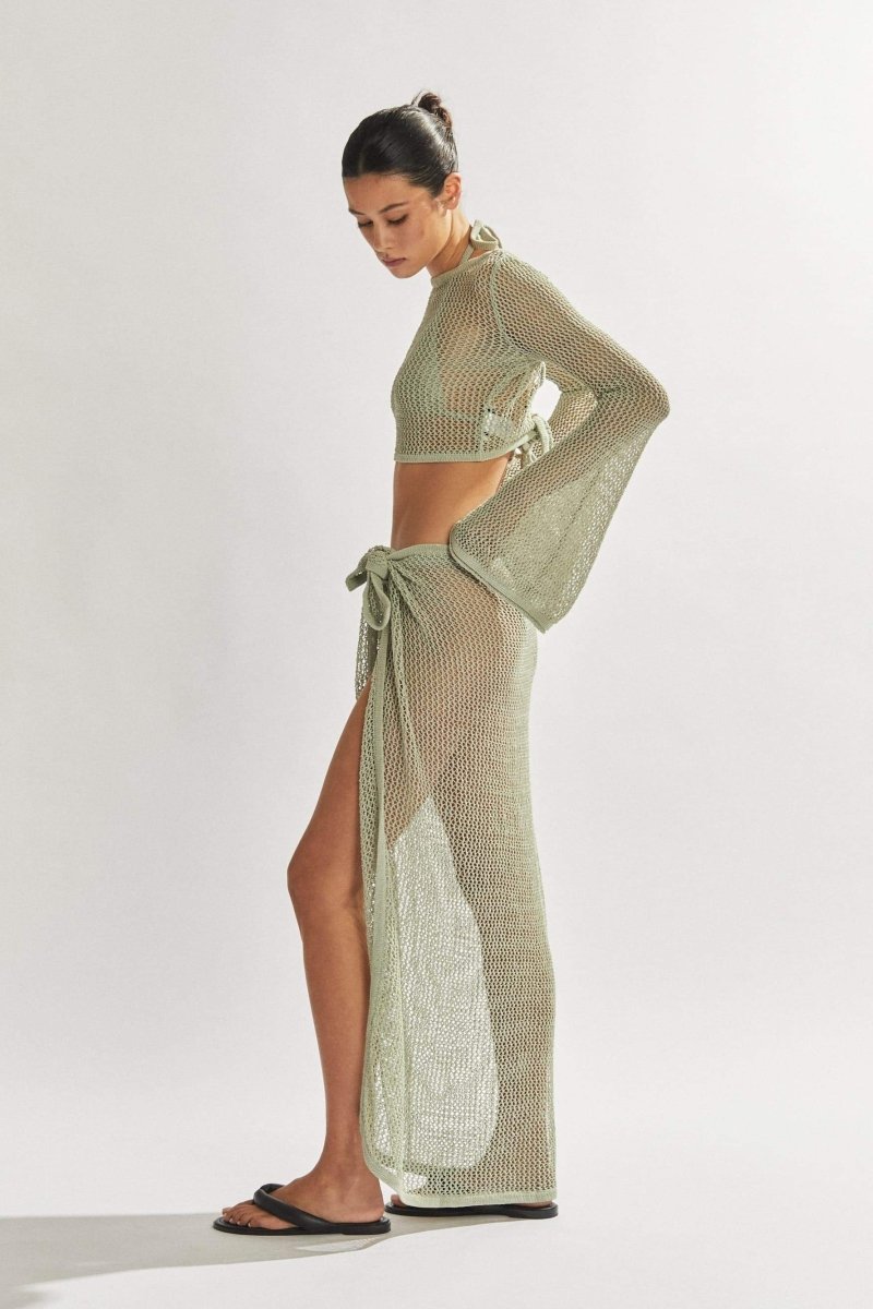 Woman in light blue crochet knit crop top and maxi skirt.