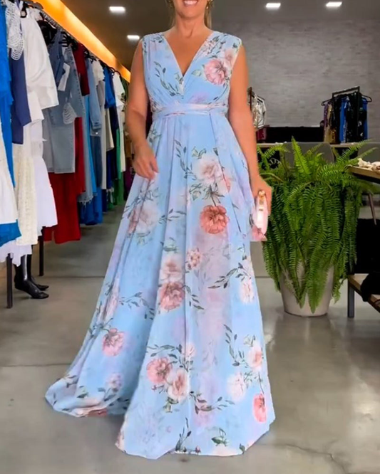 Light Blue - A woman wearing a sleeveless light blue chiffon maxi dress featuring a soft pink rose floral print, a V-neckline, and a defined banded waist.