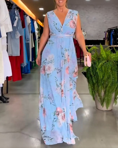 Light Blue - A woman wearing a sleeveless light blue chiffon maxi dress featuring a soft pink rose floral print, a V-neckline, and a defined banded waist.