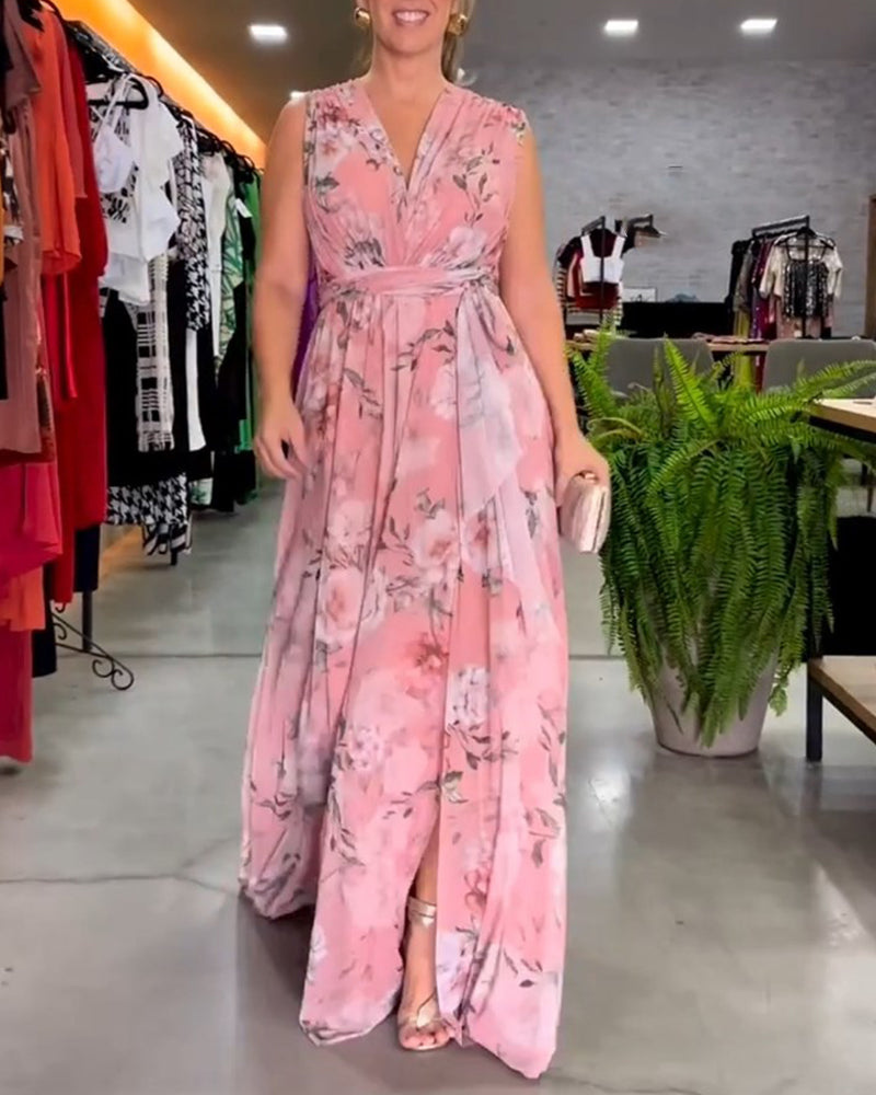Pink - A woman wearing a sleeveless light blue chiffon maxi dress featuring a soft pink rose floral print, a V-neckline, and a defined banded waist.