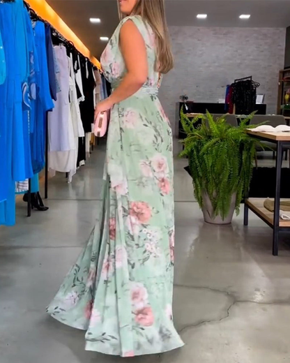 Sage Green - A woman wearing a sleeveless light blue chiffon maxi dress featuring a soft pink rose floral print, a V-neckline, and a defined banded waist.