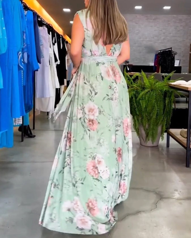 Sage Green - A woman wearing a sleeveless light blue chiffon maxi dress featuring a soft pink rose floral print, a V-neckline, and a defined banded waist.