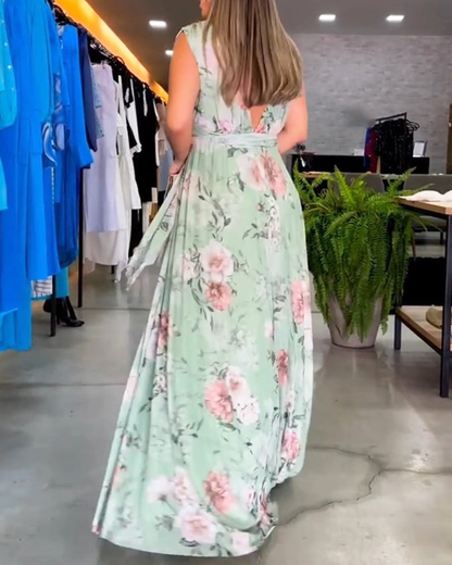 Sage Green - A woman wearing a sleeveless light blue chiffon maxi dress featuring a soft pink rose floral print, a V-neckline, and a defined banded waist.