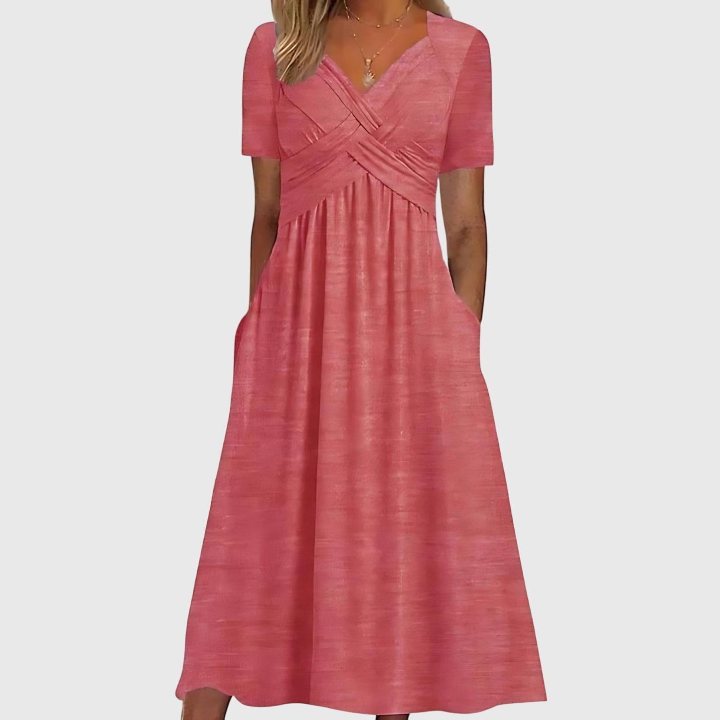 Pink - A woman wearing a cornflower blue midi-length jersey dress featuring a criss-cross ruched bodice, short sleeves, and a flowy skirt with side pockets.