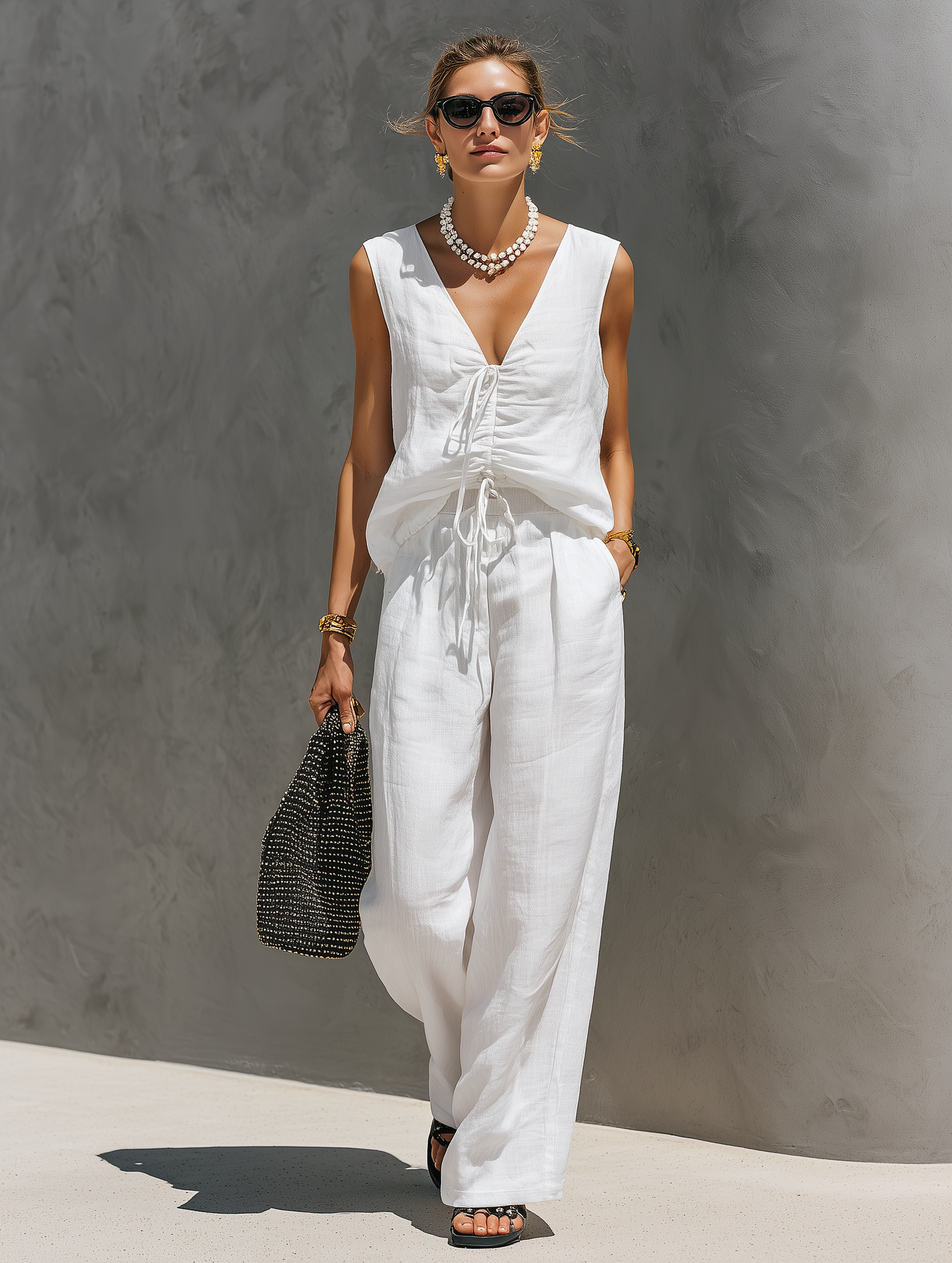 White - A woman wearing a matching sleeveless ruched top with front drawstrings and relaxed wide-leg pants in a textured woven fabric.