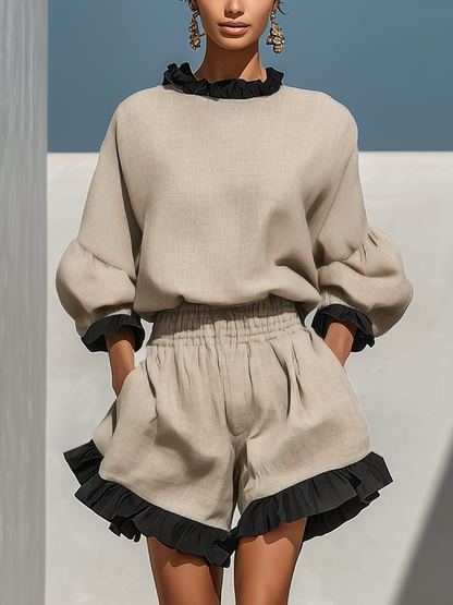 Beige - Woman walking outdoors wearing a woven shorts set featuring a high ruffled neckline, long balloon sleeves, and flared shorts with contrast ruffle trim.