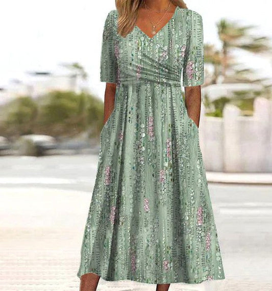 Green - A woman wearing a sage green midi dress with a vertical floral stripe print, featuring a V-neckline, ruched waist, short sleeves, and side pockets.