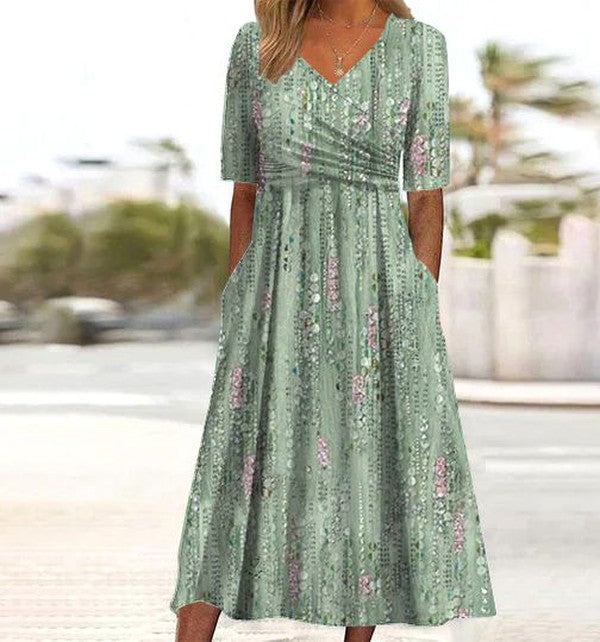 Green - A woman wearing a sage green midi dress with a vertical floral stripe print, featuring a V-neckline, ruched waist, short sleeves, and side pockets.