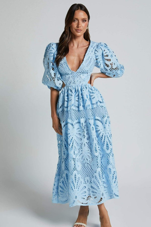 Woman in yellow lace maxi dress with puff sleeves and cut-out waist.