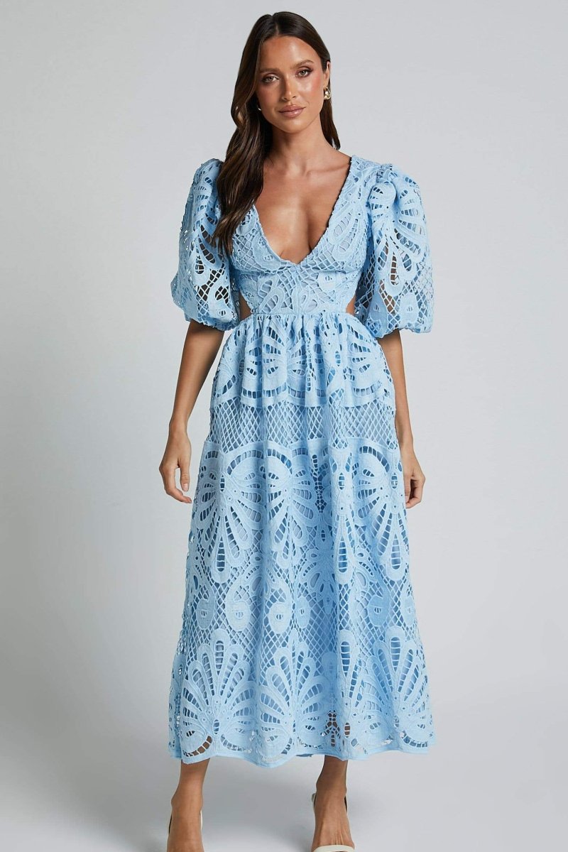 Woman in yellow lace maxi dress with puff sleeves and cut-out waist.