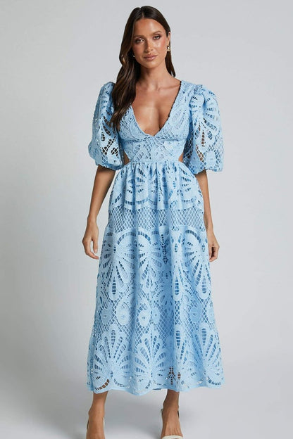 Woman in yellow lace maxi dress with puff sleeves and cut-out waist.
