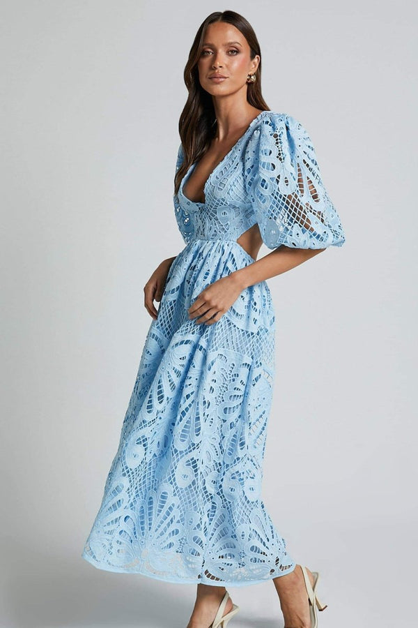 Woman in yellow lace maxi dress with puff sleeves and cut-out waist.