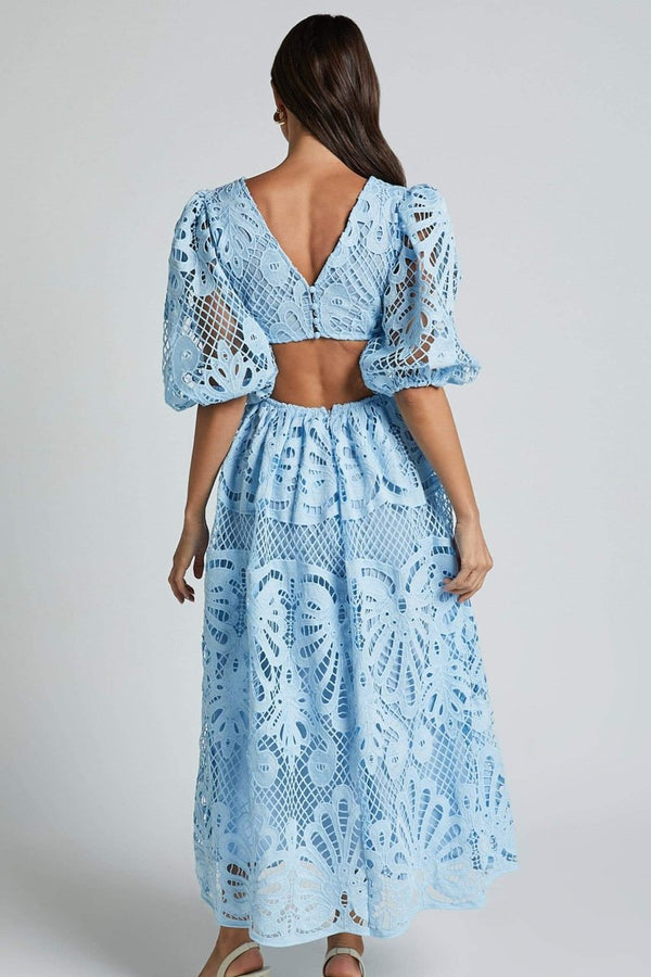 Woman in yellow lace maxi dress with puff sleeves and cut-out waist.