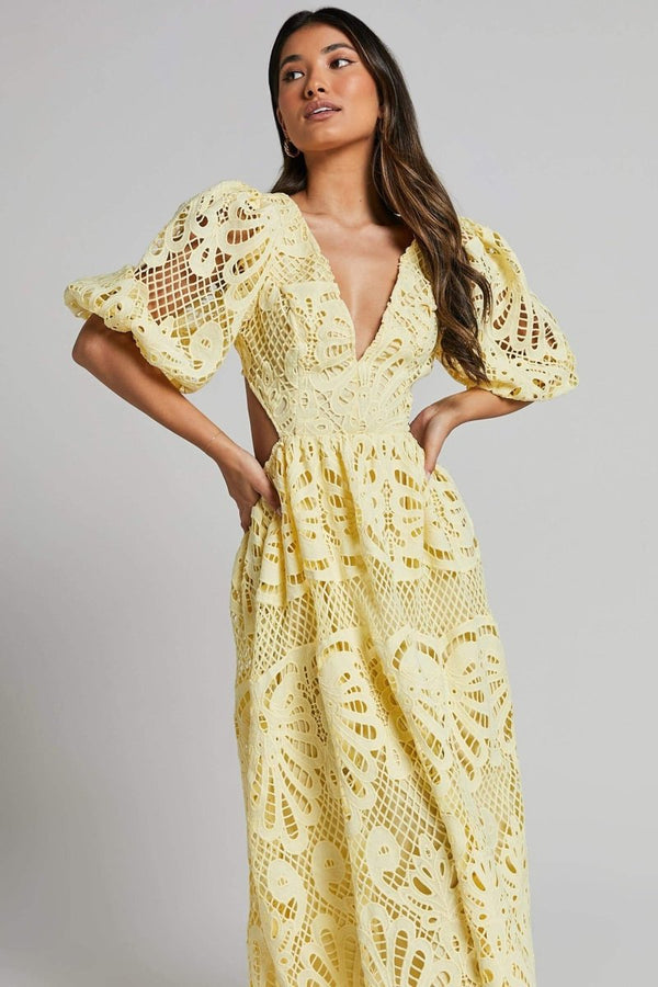 Woman in yellow lace maxi dress with puff sleeves and cut-out waist.