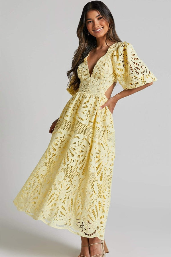 Woman in yellow lace maxi dress with puff sleeves and cut-out waist.